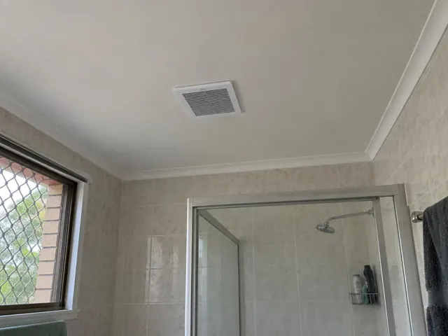 Bathroom ceiling exhaust fan in a tiled shower room with window and glass shower screen in Oxenford